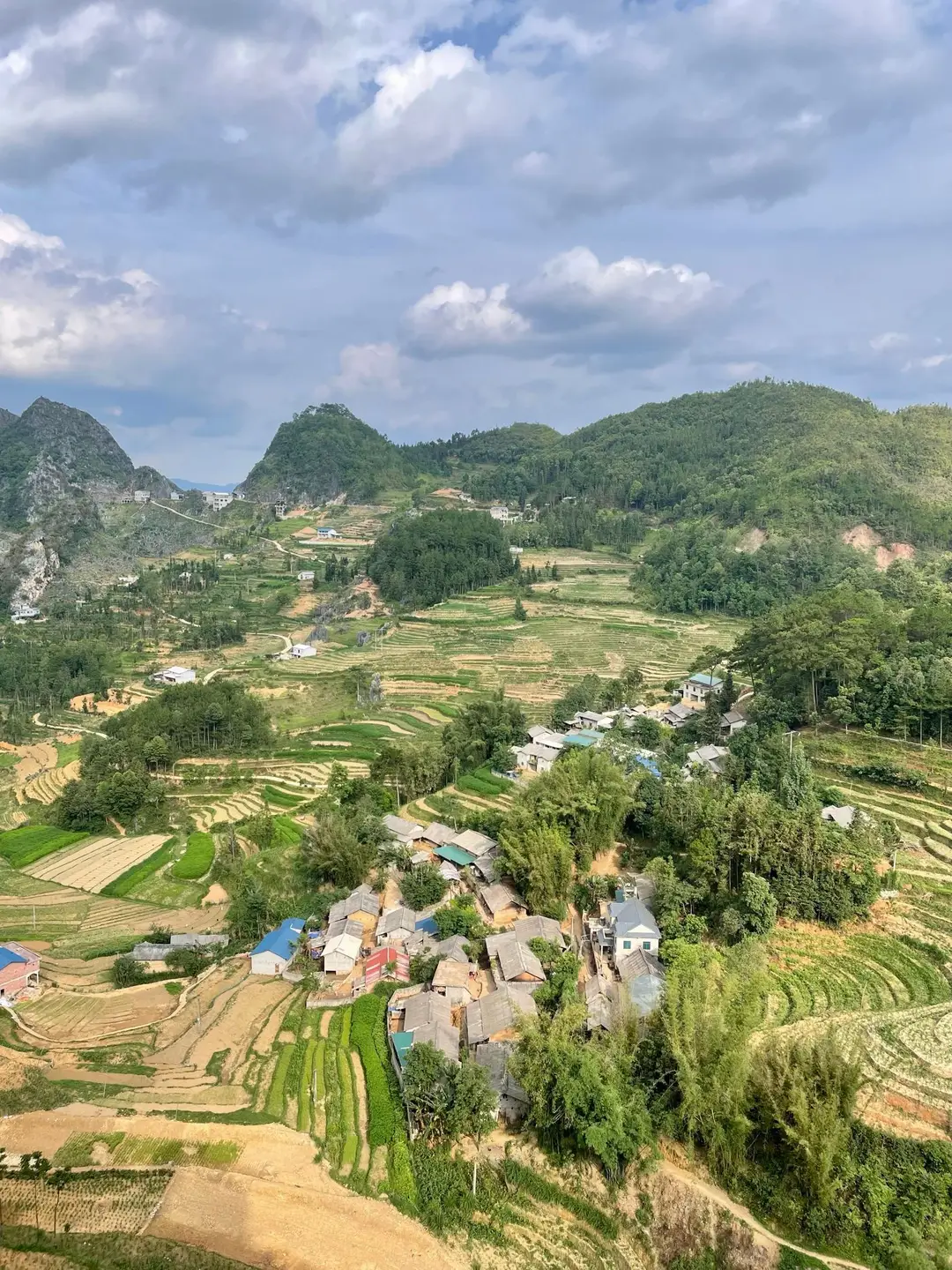 Vue aérienne d'un village traditionnel niché au cœur de collines verdoyantes et de rizières en terrasses sculptées dans la province de Ha Giang au Vietnam.