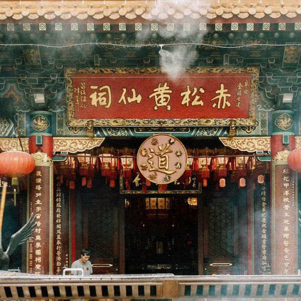 Entrée ornée du temple taoïste Wong Tai Sin à Kowloon, montrant des lanternes rouges, des inscriptions calligraphiées et de la fumée d'encens rituelle.