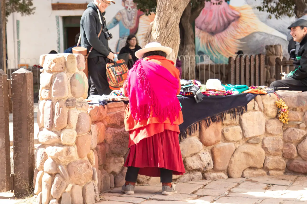 Voyage en Argentine – Femme d'une communauté andine en costume traditionnel devant un marché d'artisanat local à Humahuaca.