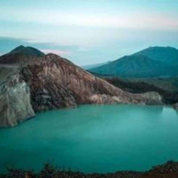 Voyage en Asie — Lac acide du cratère Kawah Ijen à Java, Indonésie : eau turquoise, parois abruptes et fumées sulfureuses dans un paysage volcanique étendu.