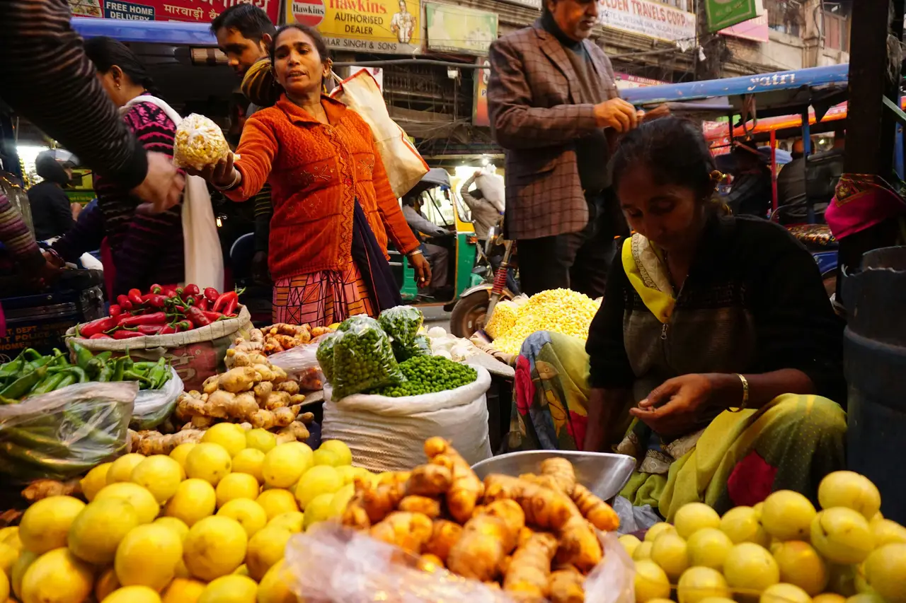 Étal coloré au marché de Delhi avec des citrons jaunes, du gingembre frais et des piments rouges mis en avant dans une ambiance de rue animée en Inde du Nord.