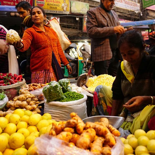 Étal coloré au marché de Delhi avec des citrons jaunes, du gingembre frais et des piments rouges mis en avant dans une ambiance de rue animée en Inde du Nord.