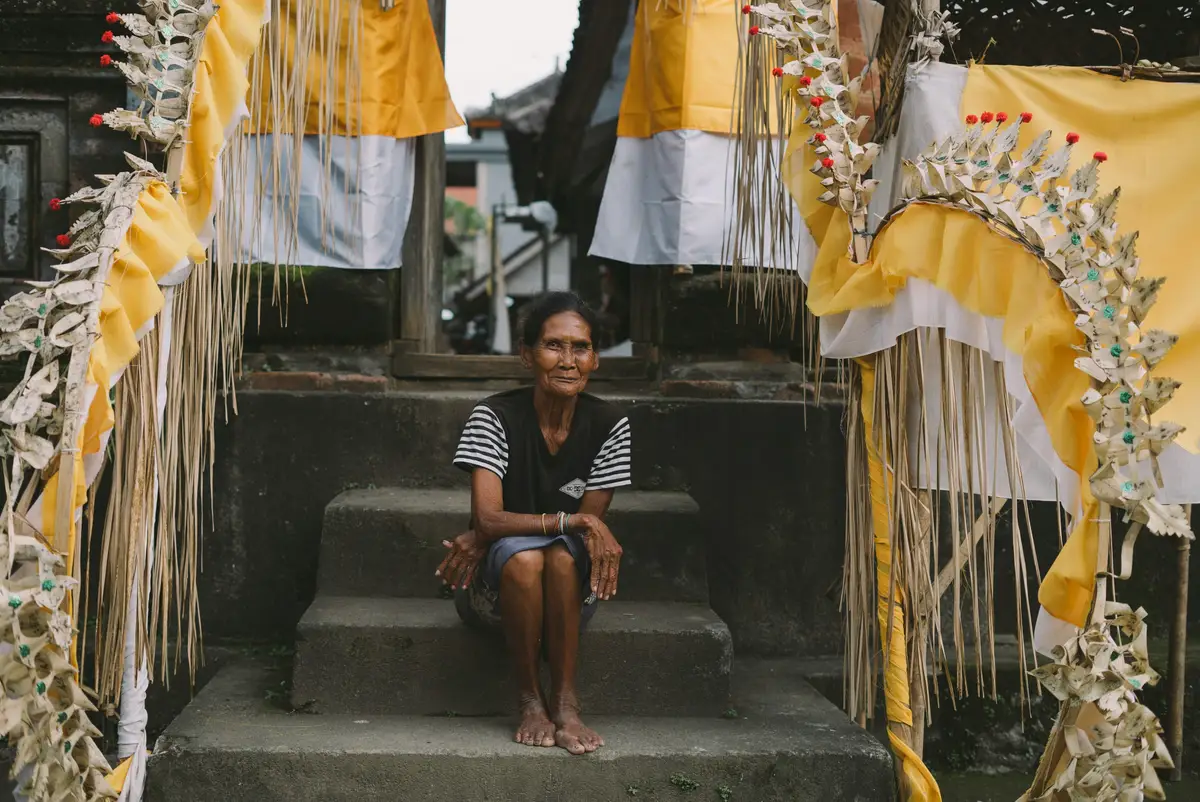 Voyage en Asie — scène authentique à Ubud avec une habitante assise parmi des décorations rituelles balinaises, reflet de la culture locale grâce à notre expertise du voyage sur mesure — Shanti Travel