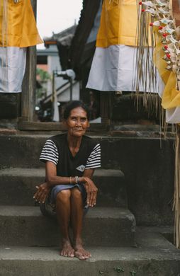 Voyage en Asie — scène authentique à Ubud avec une habitante assise parmi des décorations rituelles balinaises, reflet de la culture locale grâce à notre expertise du voyage sur mesure — Shanti Travel