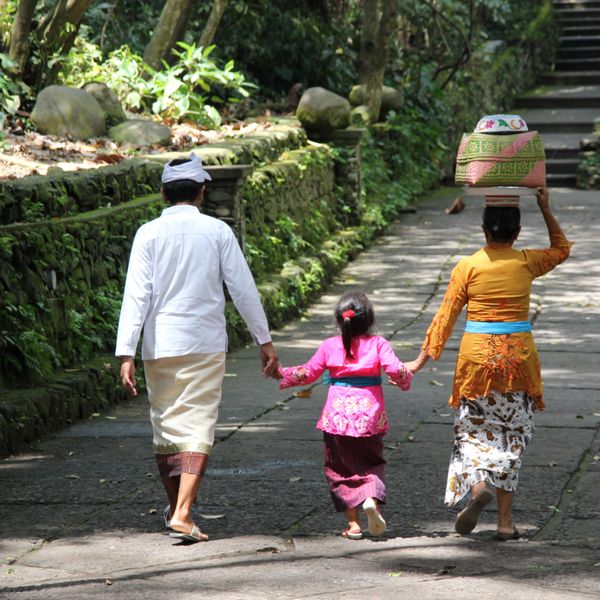 Voyage en Asie - famille en voyage en Indonésie à Bali marchant ensemble sur un chemin traditionnel