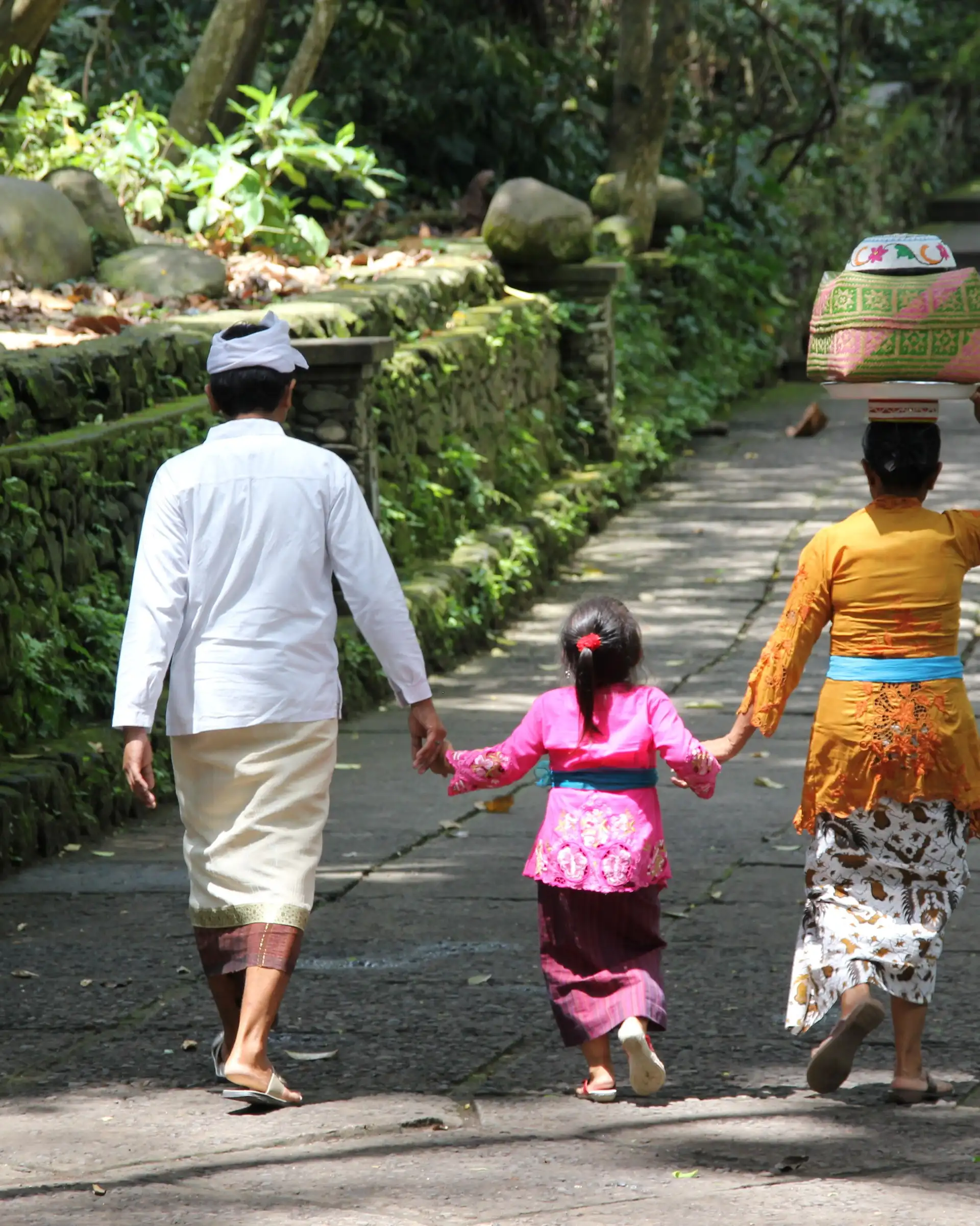 Voyage en Asie - famille en voyage en Indonésie à Bali marchant ensemble sur un chemin traditionnel