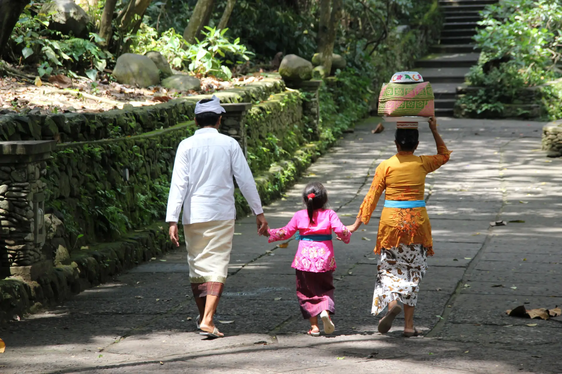Voyage en Asie - famille en voyage en Indonésie à Bali marchant ensemble sur un chemin traditionnel