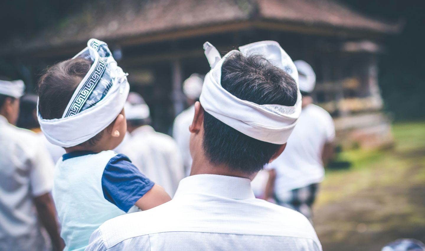 Voyage en Asie — Une famille balinaise vêtue de tenues traditionnelles observant une cérémonie locale dans un temple.