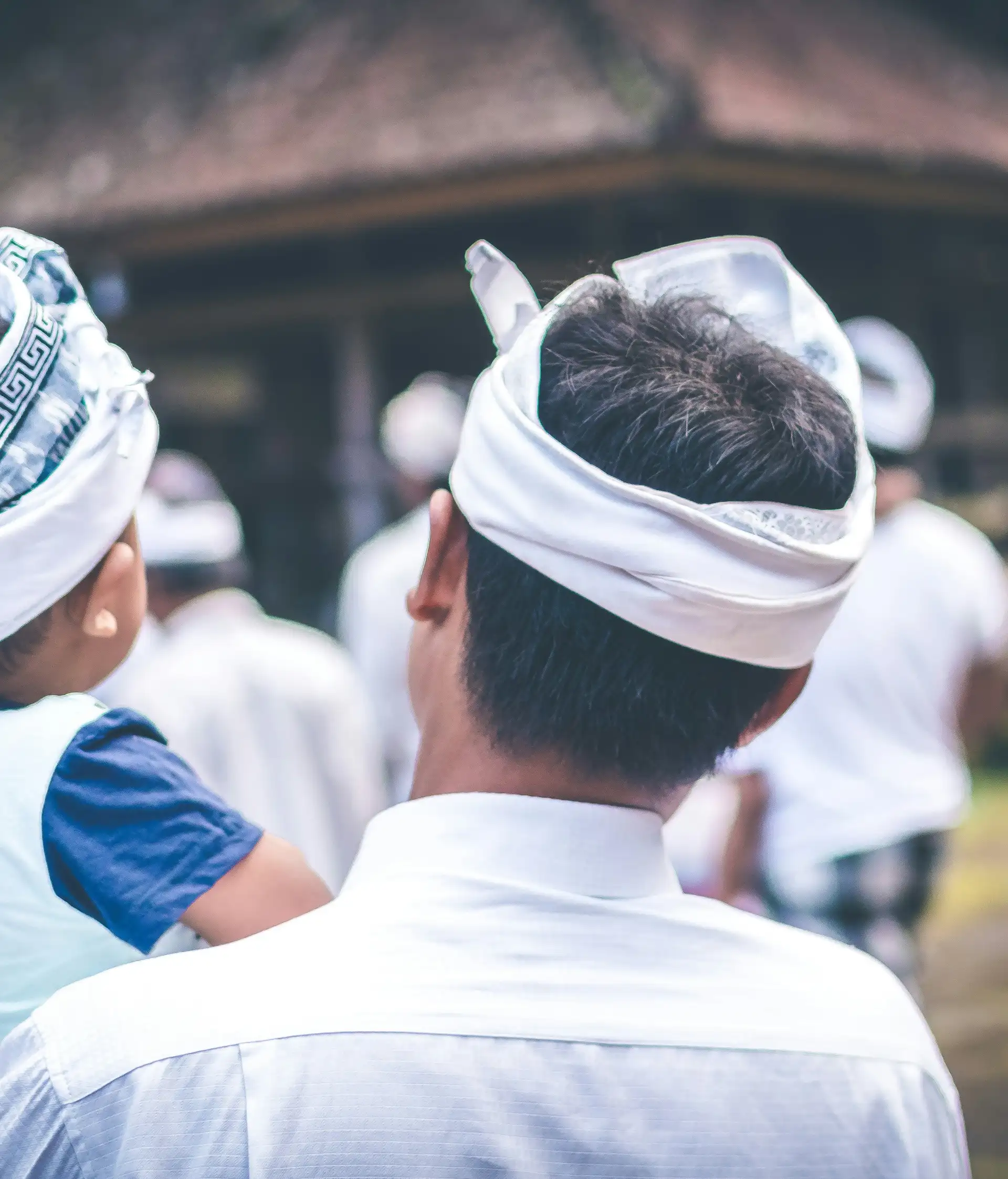 Voyage en Asie — Une famille balinaise vêtue de tenues traditionnelles observant une cérémonie locale dans un temple.