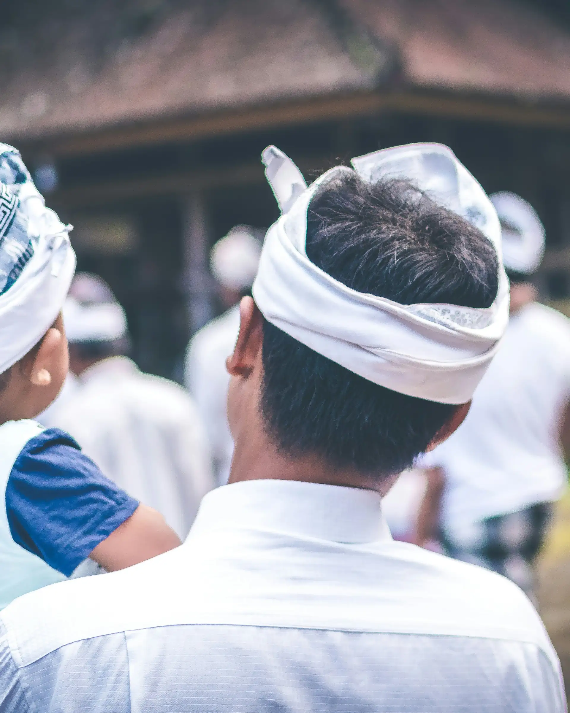 Voyage en Asie — Une famille balinaise vêtue de tenues traditionnelles observant une cérémonie locale dans un temple.