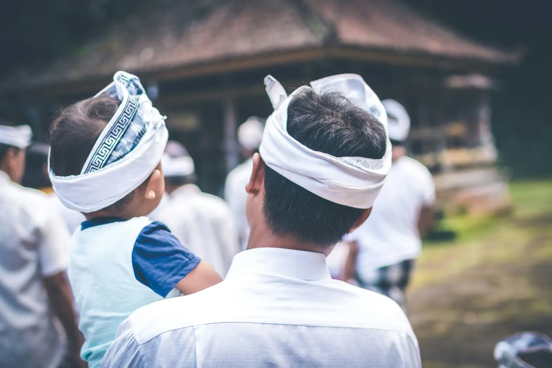 Voyage en Asie — Une famille balinaise vêtue de tenues traditionnelles observant une cérémonie locale dans un temple.