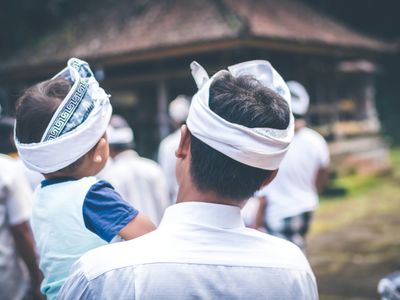 Voyage en Asie — Une famille balinaise vêtue de tenues traditionnelles observant une cérémonie locale dans un temple.