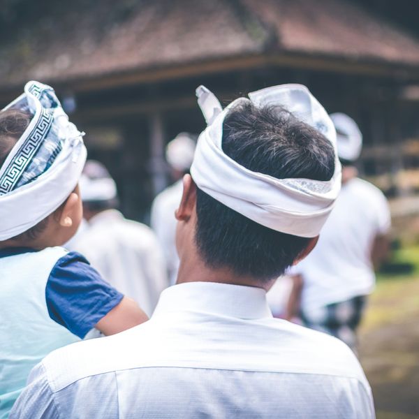 Voyage en Asie — Une famille balinaise vêtue de tenues traditionnelles observant une cérémonie locale dans un temple.
