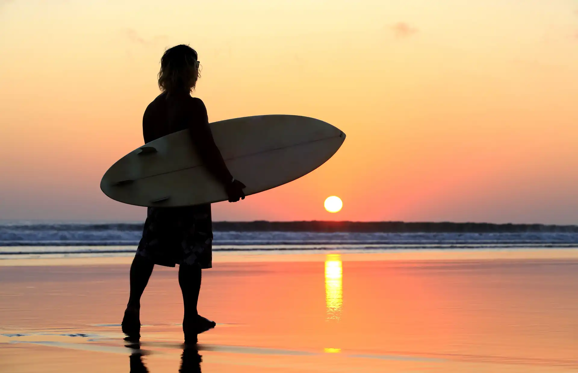 Voyage en Asie — Surfeur au coucher du soleil sur une plage de Bali, idéal pour un voyage d'été et d'aventure — Shanti Travel