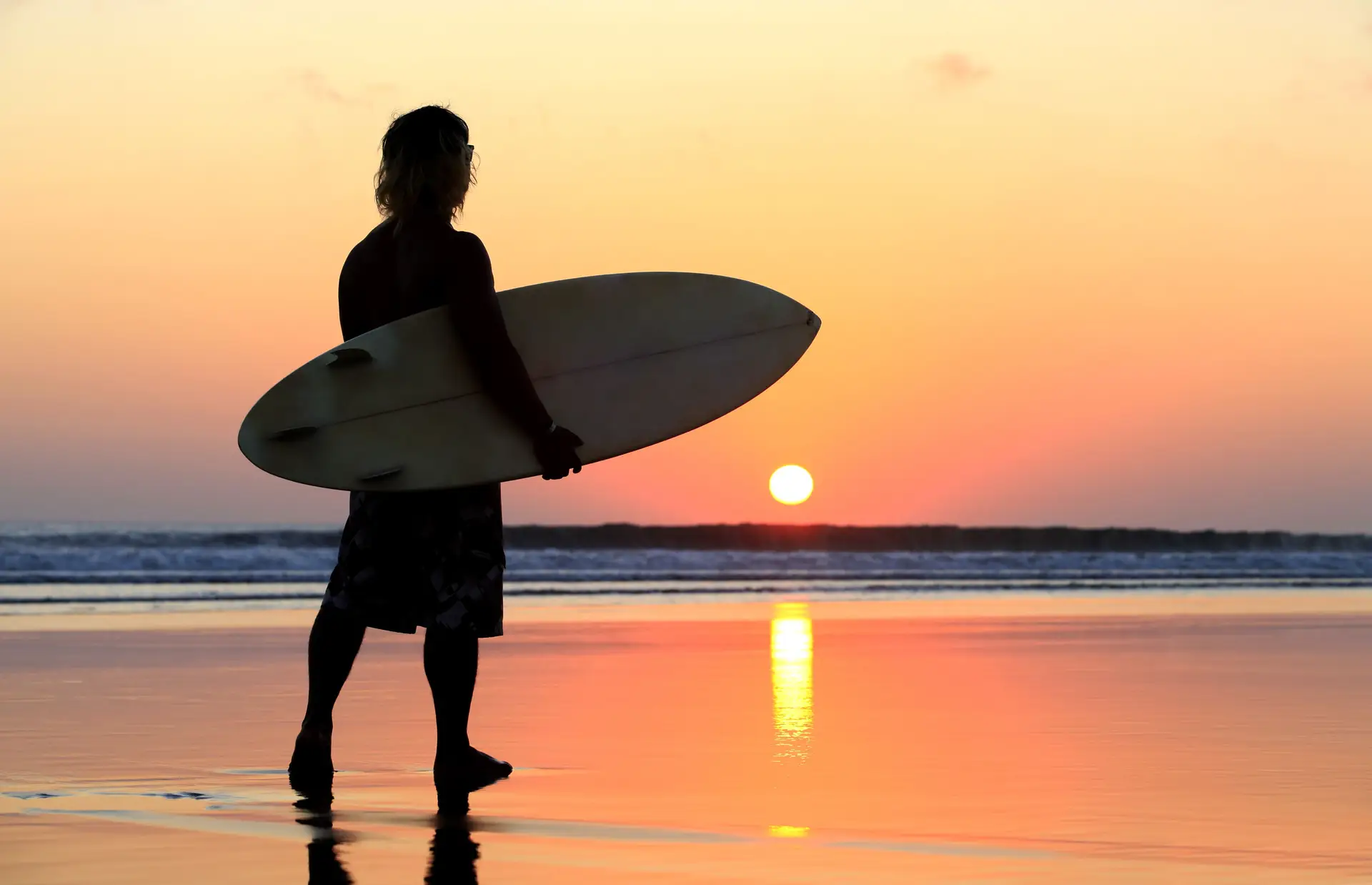 Voyage en Asie — Surfeur au coucher du soleil sur une plage de Bali, idéal pour un voyage d'été et d'aventure — Shanti Travel