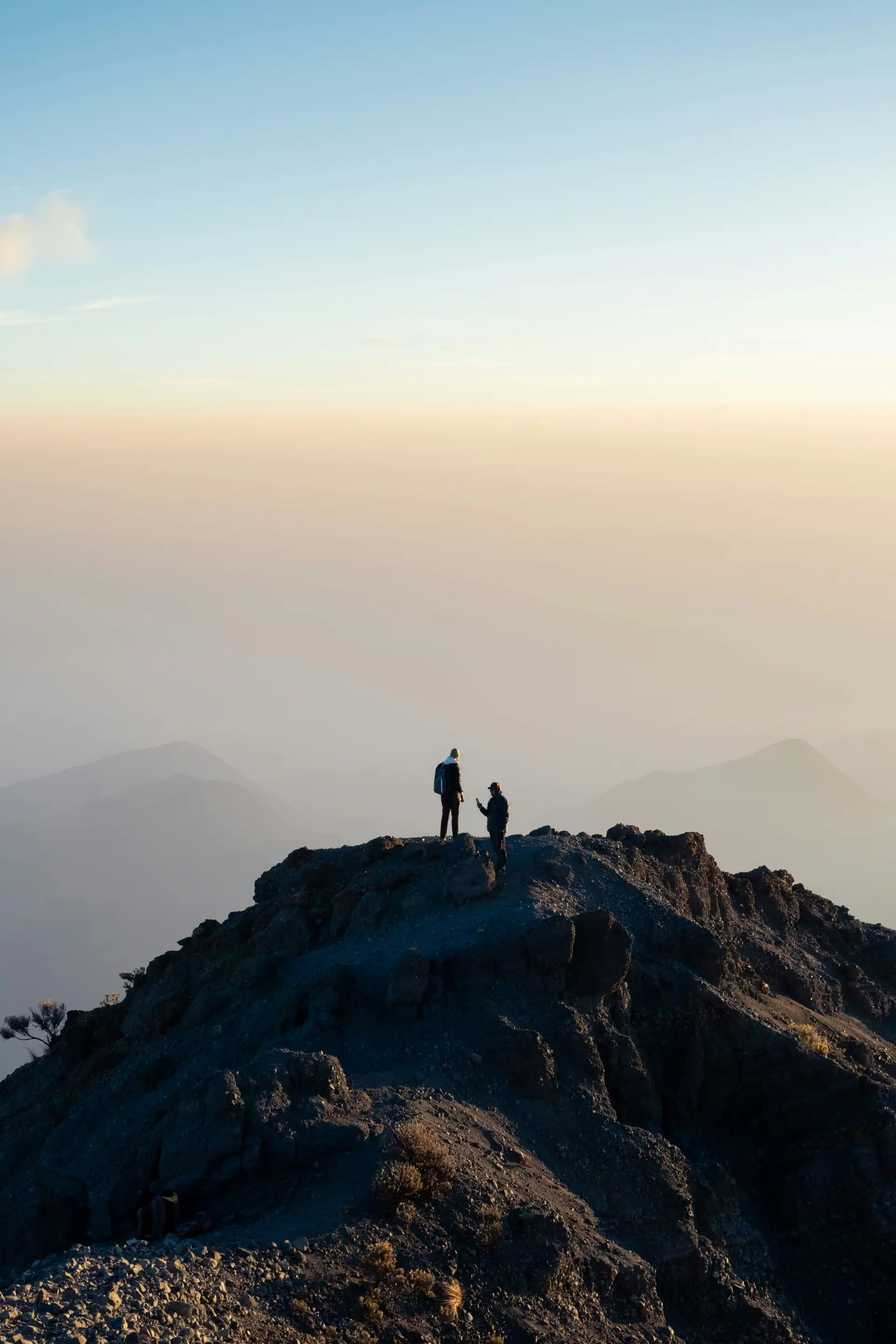 Travel in Asia - Two hikers stand on the summit of Mount Rinjani surrounded by a sea of clouds in Lombok, Indonesia