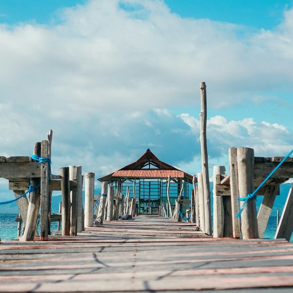 Voyage en Asie — pont en bois menant à un petit abri au bord de la mer aux Moluques en Indonésie, une expérience authentique guidée par notre expertise locale — Shanti Travel