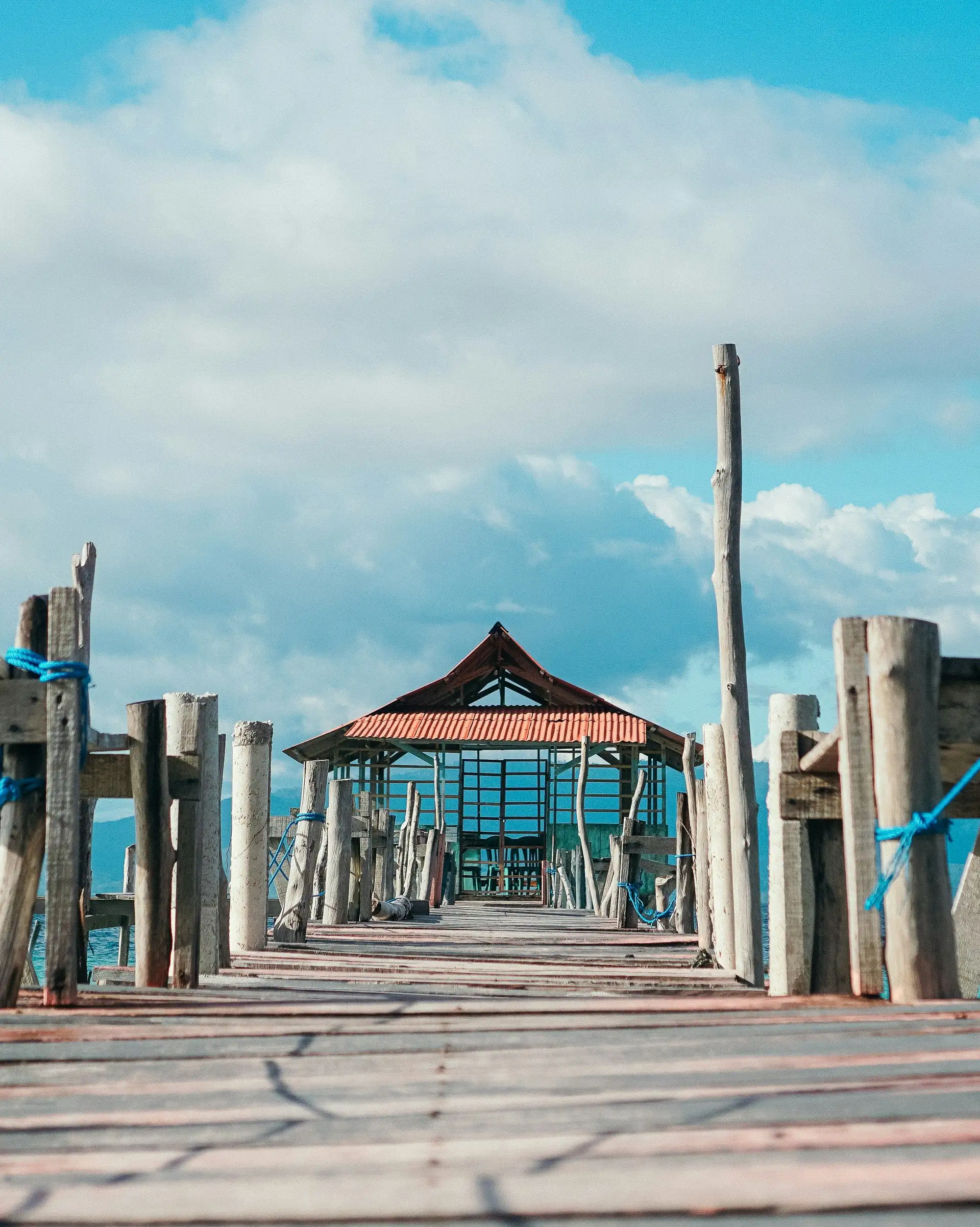 Voyage en Asie — pont en bois menant à un petit abri au bord de la mer aux Moluques en Indonésie, une expérience authentique guidée par notre expertise locale — Shanti Travel