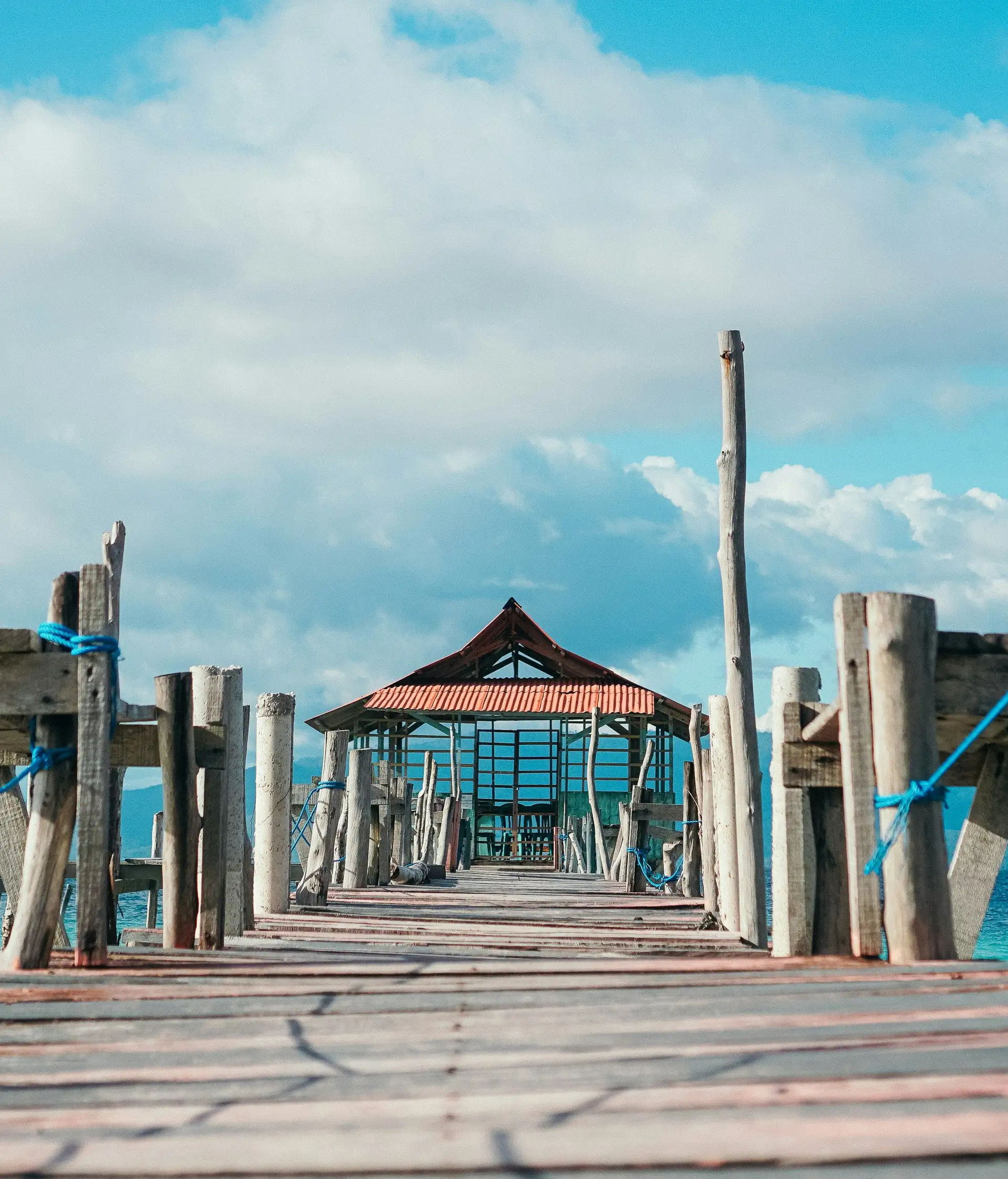 Voyage en Asie — pont en bois menant à un petit abri au bord de la mer aux Moluques en Indonésie, une expérience authentique guidée par notre expertise locale — Shanti Travel