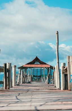 Voyage en Asie — pont en bois menant à un petit abri au bord de la mer aux Moluques en Indonésie, une expérience authentique guidée par notre expertise locale — Shanti Travel