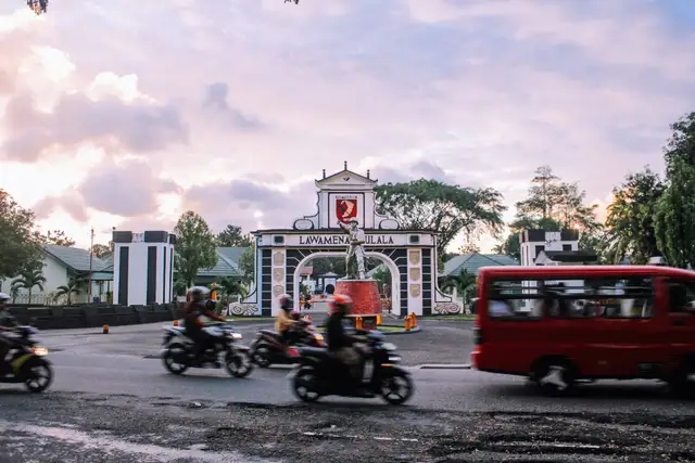 Voyage en Asie — scène urbaine animée à Ambon avec motos et minibus devant la porte emblématique de la ville, témoignage authentique de la vie locale grâce à notre expertise — Shanti Travel