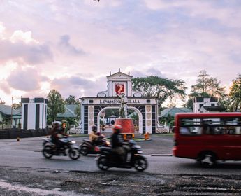 Voyage en Asie — scène urbaine animée à Ambon avec motos et minibus devant la porte emblématique de la ville, témoignage authentique de la vie locale grâce à notre expertise — Shanti Travel