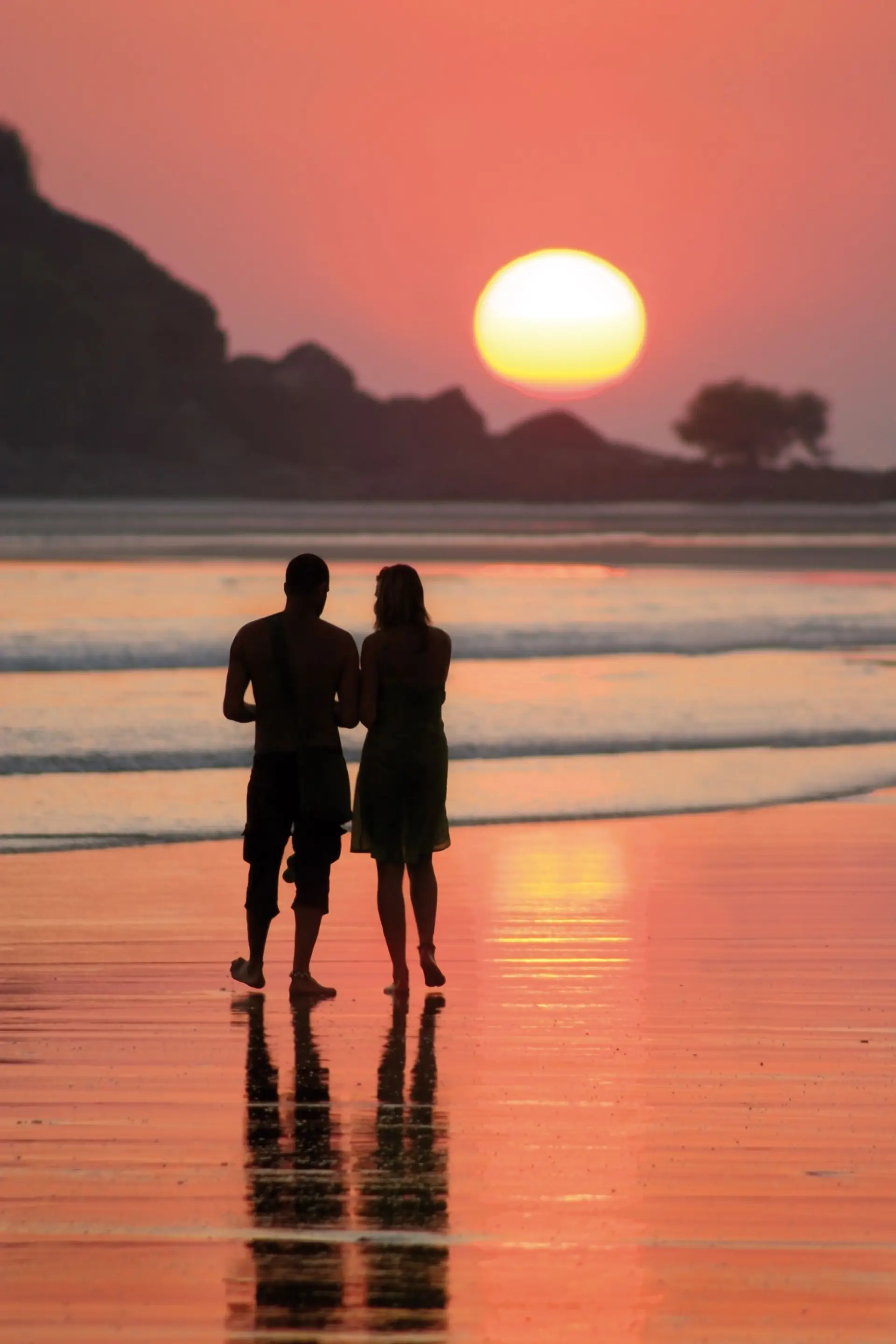 Travel in Asia - A couple standing on a beach watching the sunset in Indonesia