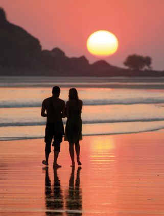 Travel in Asia - A couple standing on a beach watching the sunset in Indonesia