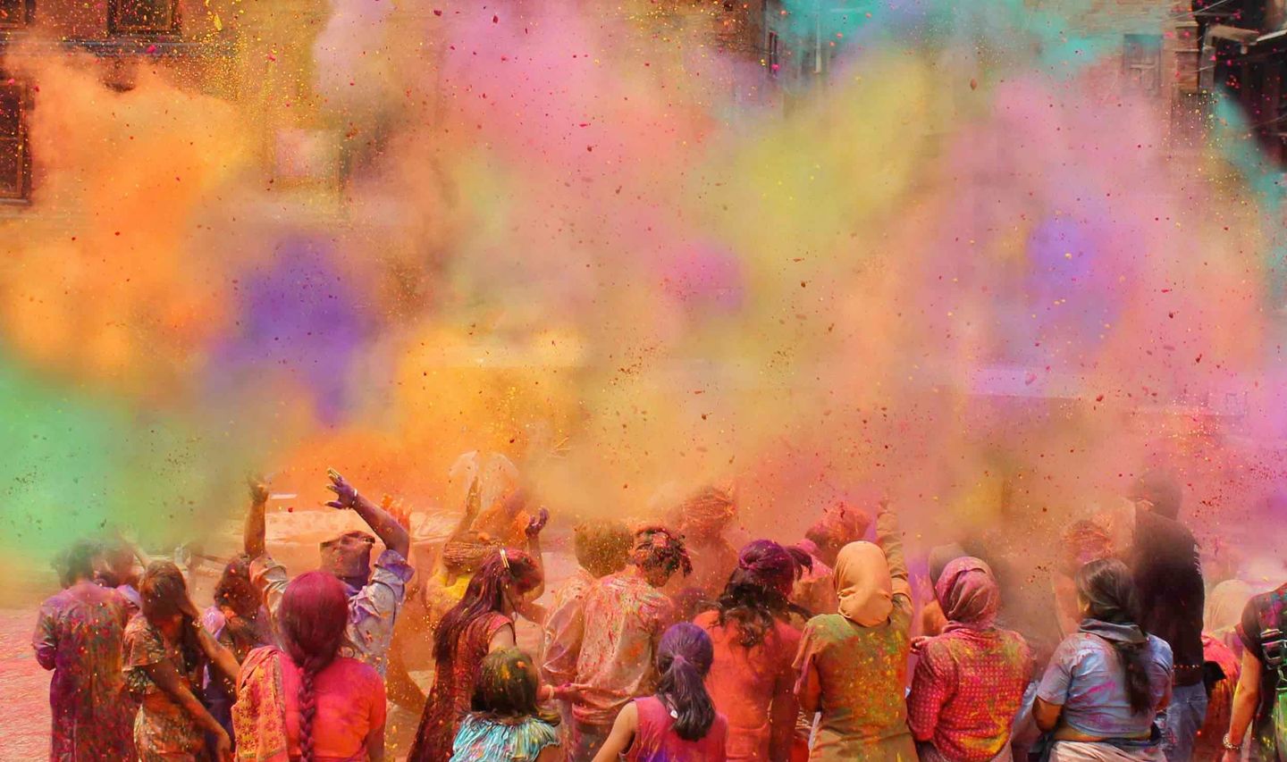 Travel in Asia - Colorful clouds of paint sprayed over a crowd during a Holi festival in India