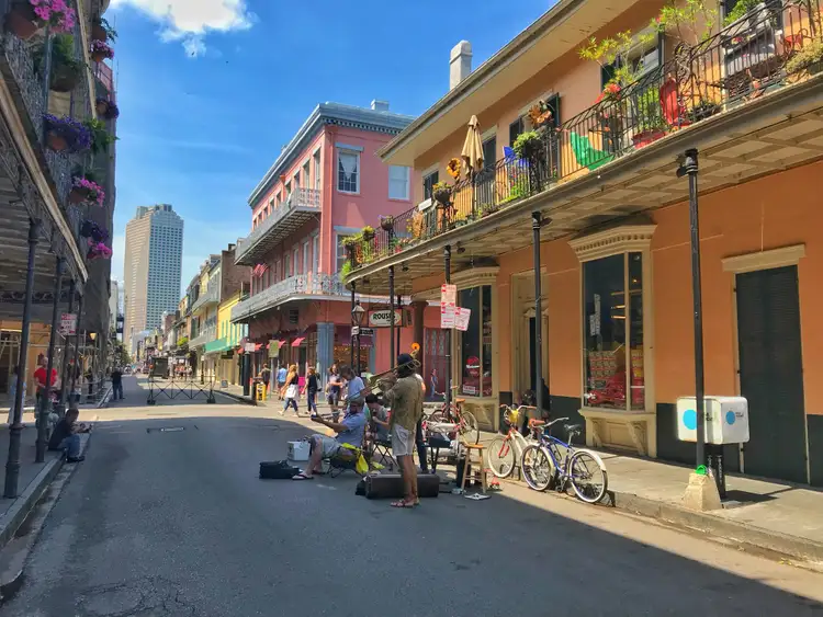 Rue animée du quartier français aux façades colorées et balcons en fer forgé sous un ciel bleu à La Nouvelle-Orléans