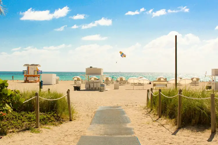 Sentier sablonneux bordé de végétation menant à la plage de South Beach avec ses cabanes de sauveteurs colorées et l'océan Atlantique