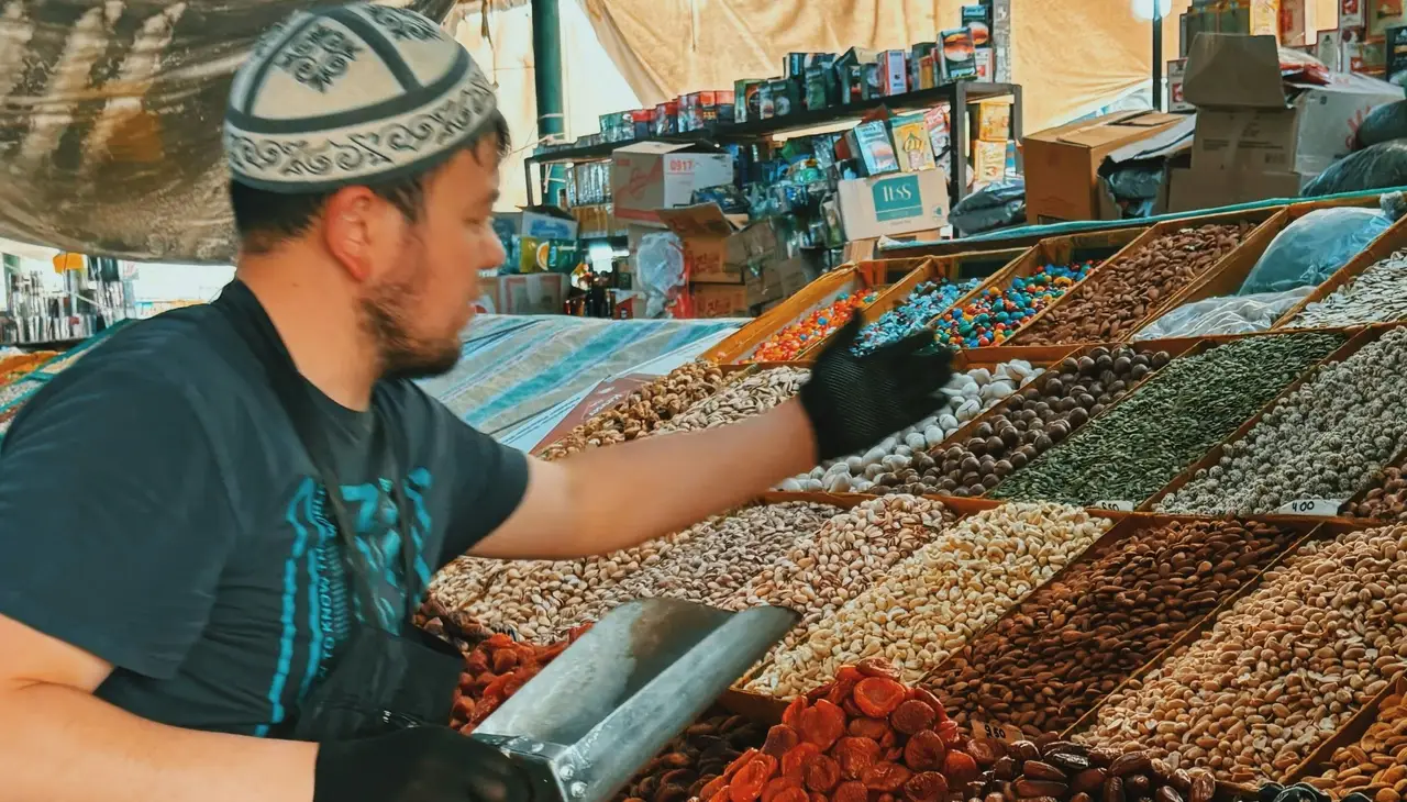 Voyage au Kirghizistan - Homme servant des épices de son stand au marché