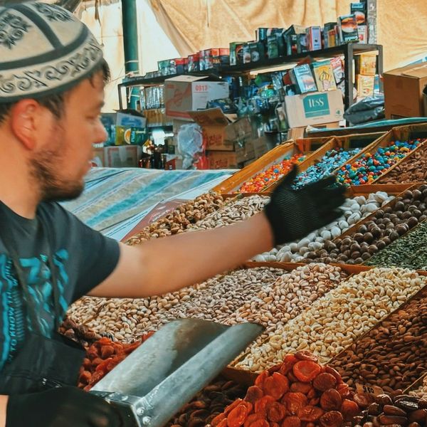 Voyage au Kirghizistan - Homme servant des épices de son stand au marché