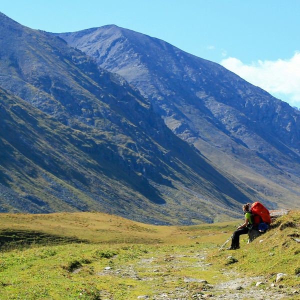 Voyage au Kirghizistan - Randonneuse faisant une pause assise face aux montagnes