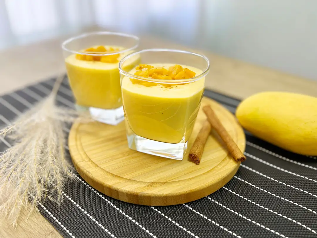 lassi à la mangue crémeux garnis de dés de mangue et de bâtons de cannelle