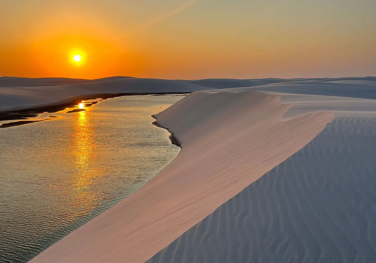 Voyage au Brésil – Coucher de soleil orange flamboyant au-dessus d'une lagune d'eau douce et des dunes de sable blanc du parc national des Lençóis Maranhenses.