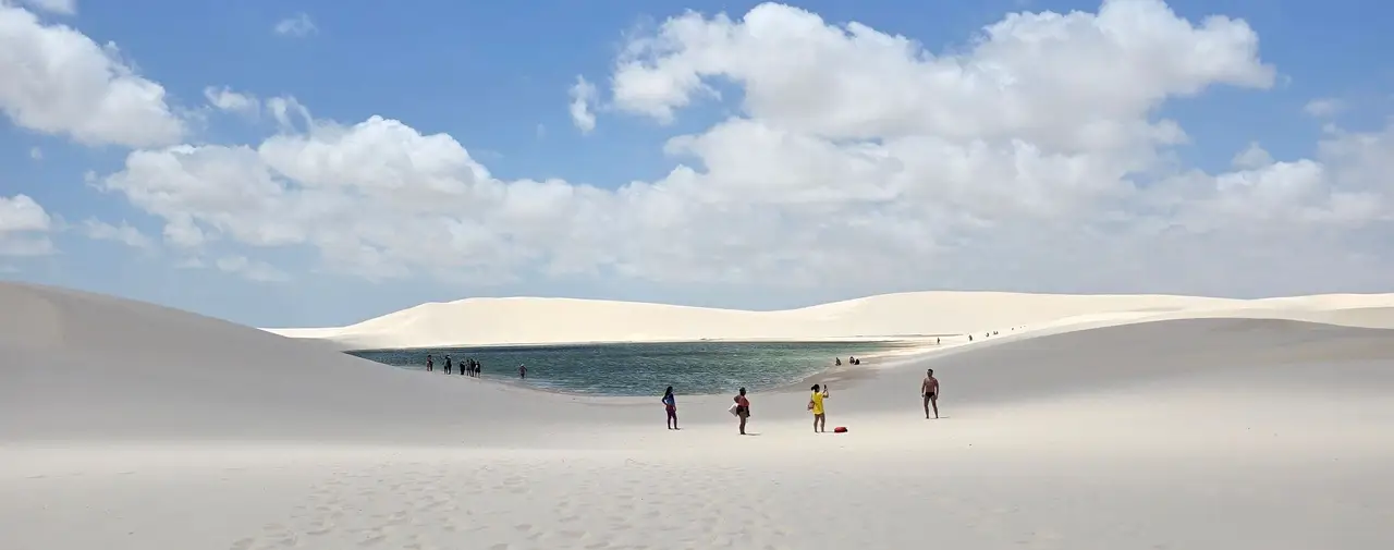 Voyage au Brésil – Des silhouettes de voyageurs marchent au milieu des immenses dunes de sable blanc et des lagunes des Petits Lençóis près de Barreirinhas.