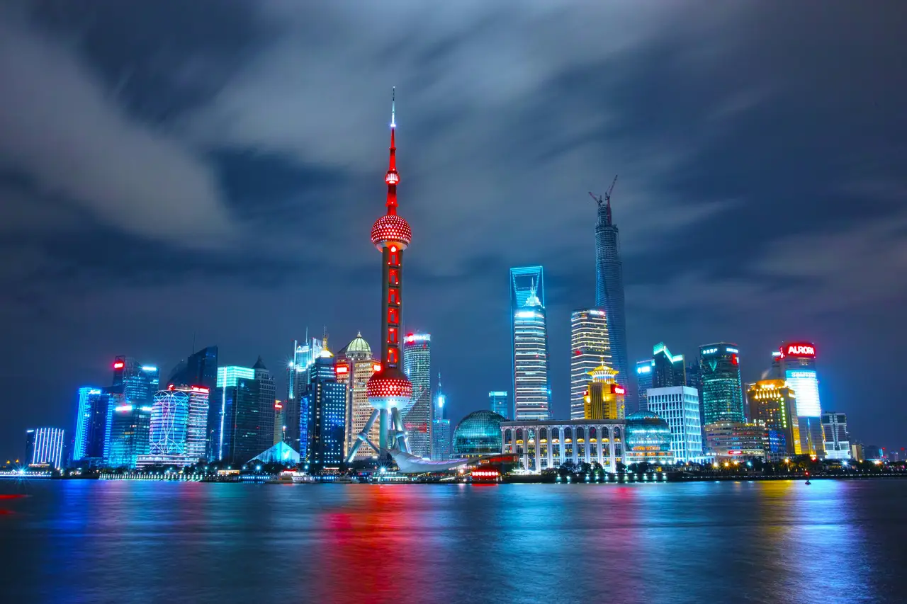 La skyline futuriste de Pudong illuminée de nuit avec la tour Perle de l'Orient se reflétant sur le fleuve Huangpu à Shanghai.