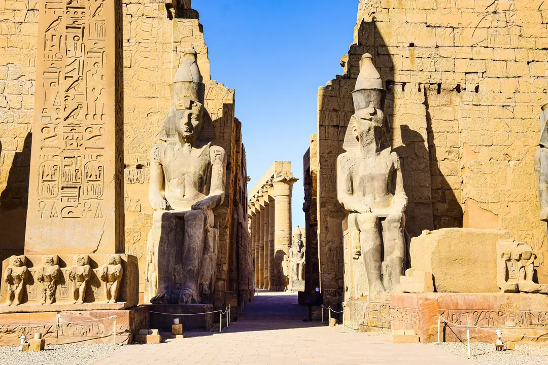 Entrée du temple de Louxor avec ses colosses de pharaons assises et son obélisque gravé de hiéroglyphes en Égypte.