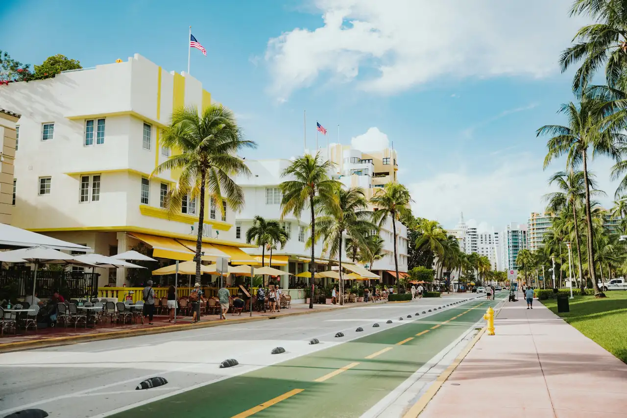Façades d'hôtels Art déco et terrasses bordées de hauts palmiers le long d'Ocean Drive à Miami Beach sous un ciel ensoleillé