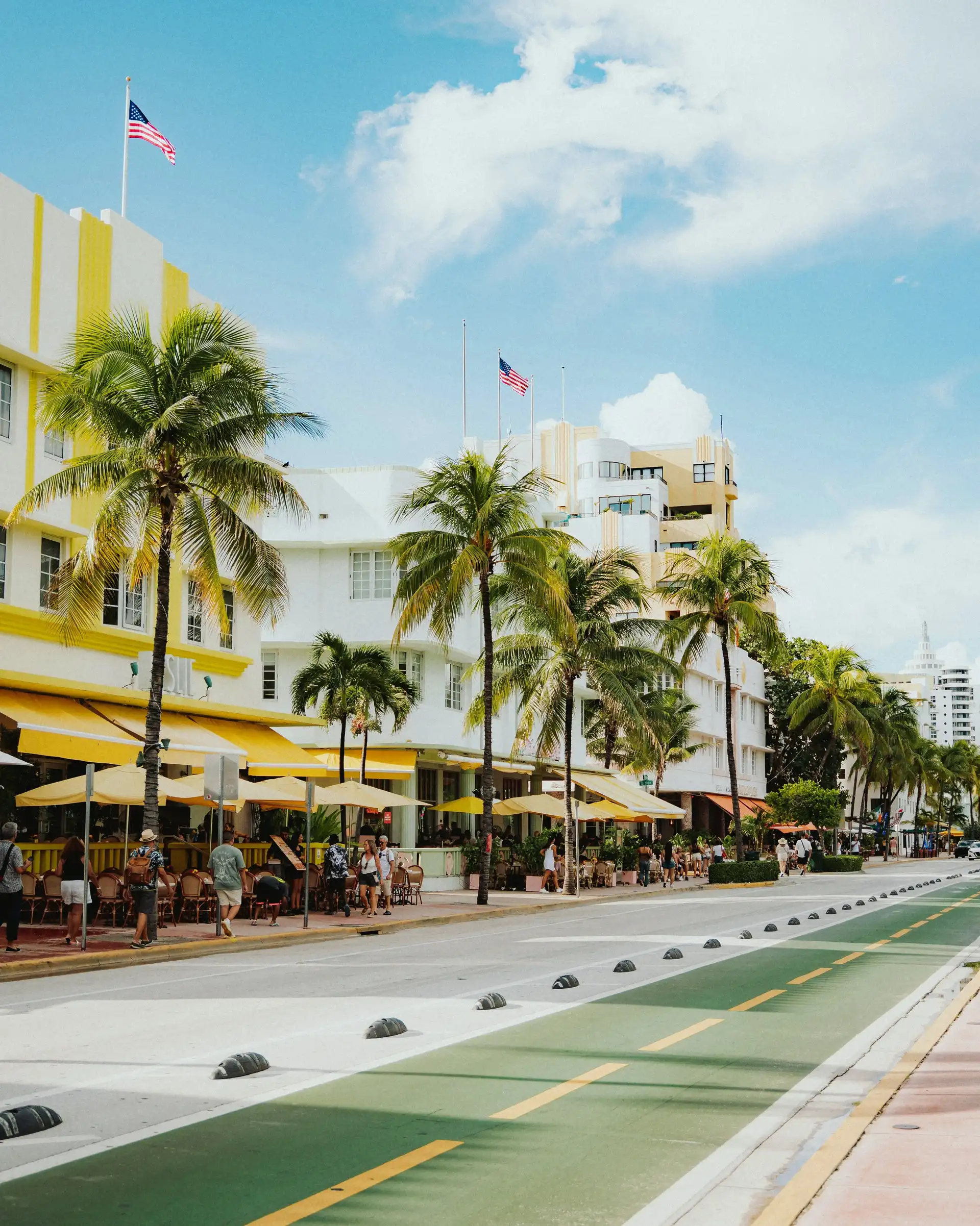 Façades d'hôtels Art déco et terrasses bordées de hauts palmiers le long d'Ocean Drive à Miami Beach sous un ciel ensoleillé