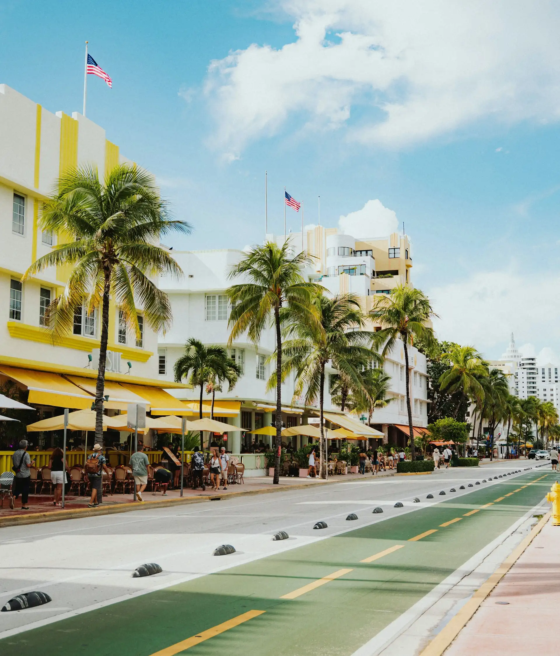 Façades d'hôtels Art déco et terrasses bordées de hauts palmiers le long d'Ocean Drive à Miami Beach sous un ciel ensoleillé