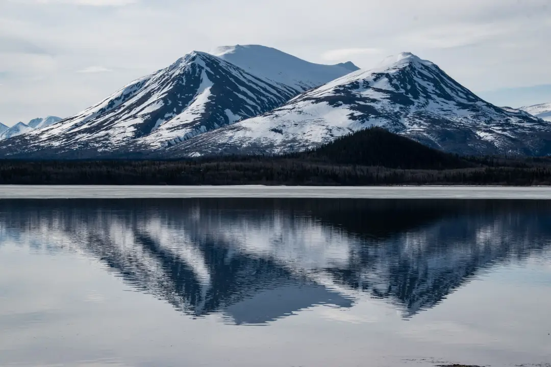 Montagnes enneigées se reflétant dans un lac du Yukon, au Canada.
