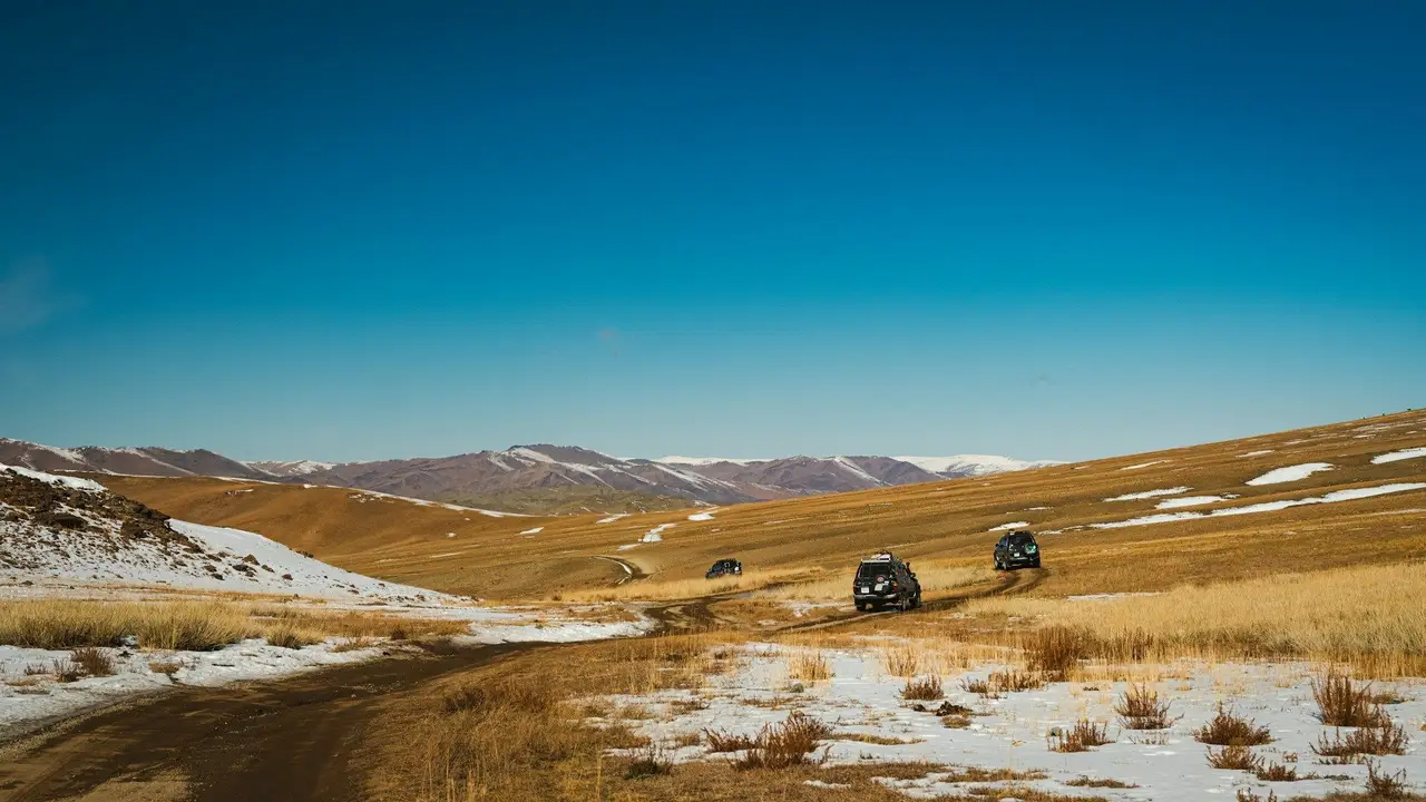 Plusieurs 4x4 sur une route de Mongolie, entre les steppes