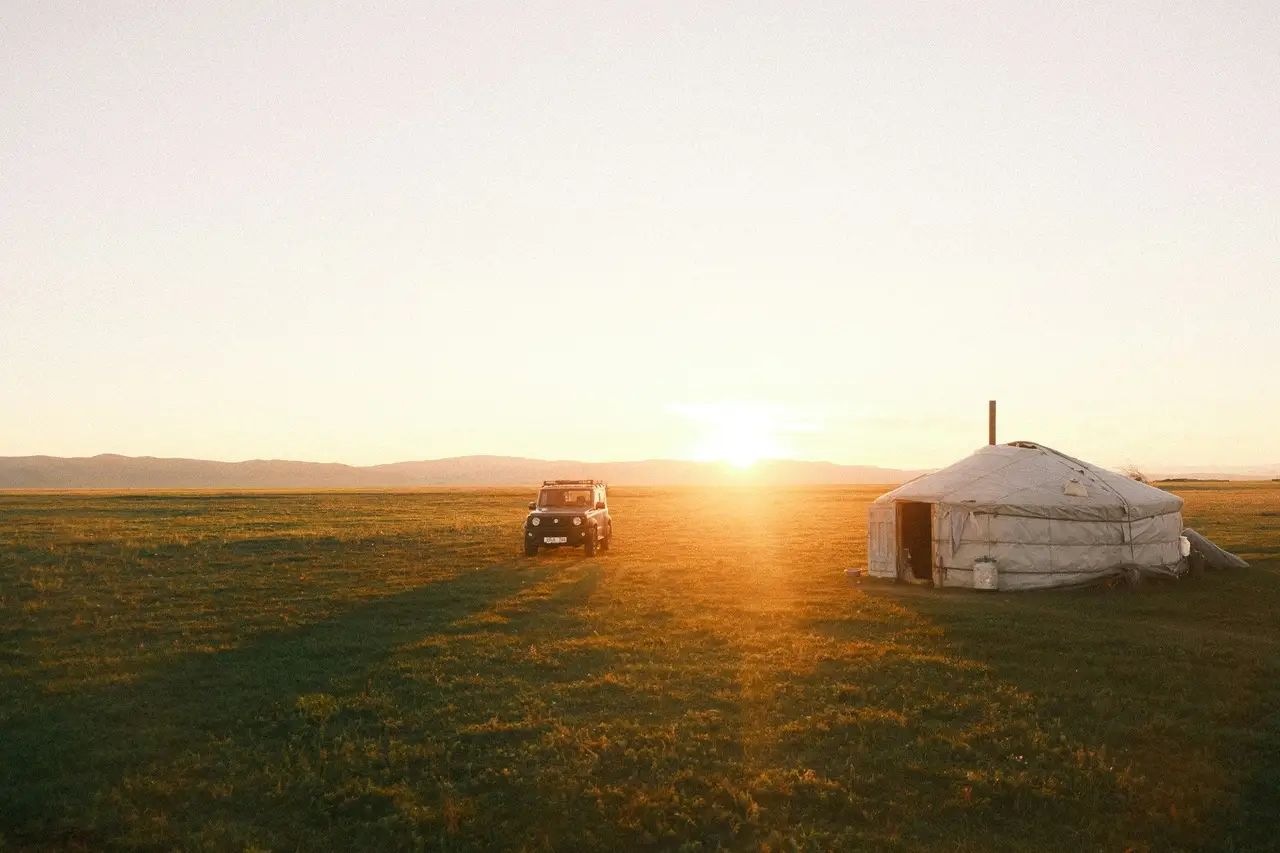 Coucher de soleil sur une yourte et un 4x4 au milieu de la steppe