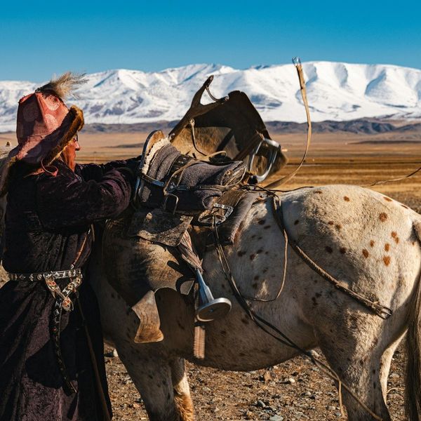 Eleveur préparant son cheval au milieu de la steppe