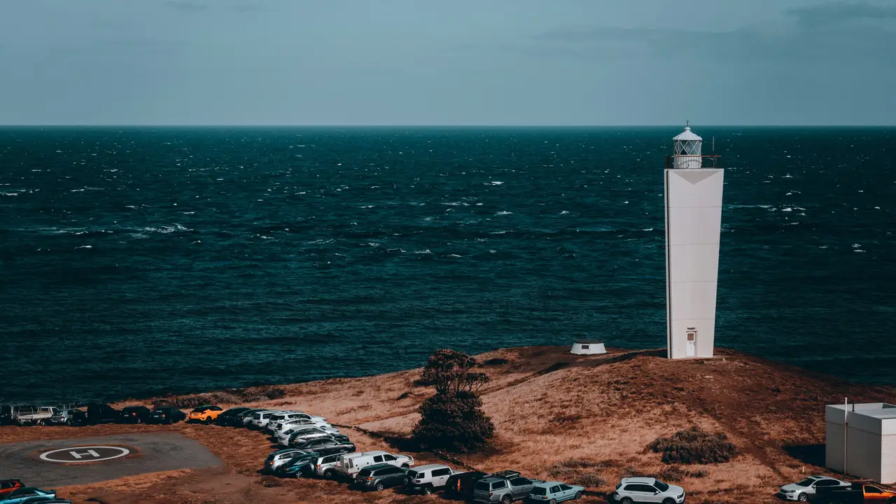 Phare moderne blanc s'élevant sur une pointe herbeuse face à l'immensité de l'océan à Cape Jervis