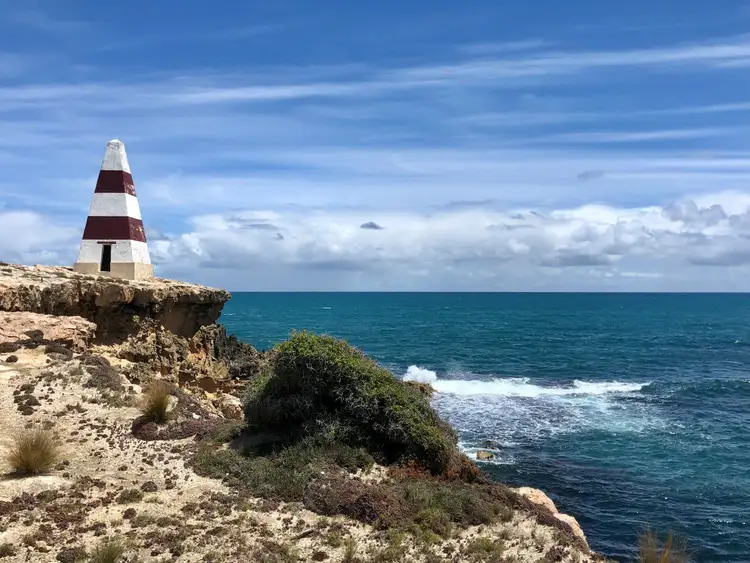 Balise de navigation pyramidale rayée rouge et blanche sur une falaise surplombant l'océan à Robe