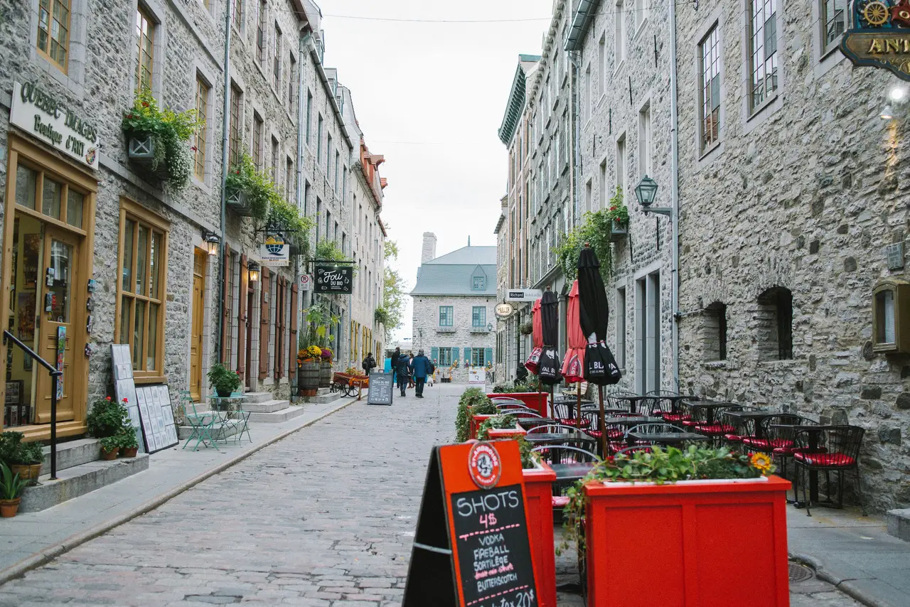 Ruelle pavée bordée de façades en pierre d'époque et de terrasses de cafés animées dans le quartier historique du Petit-Champlain
