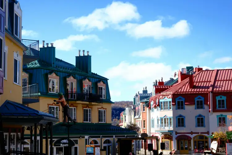 Bâtiments et toitures colorés du village piétonnier de Mont-Tremblant sous un ciel bleu nuageux